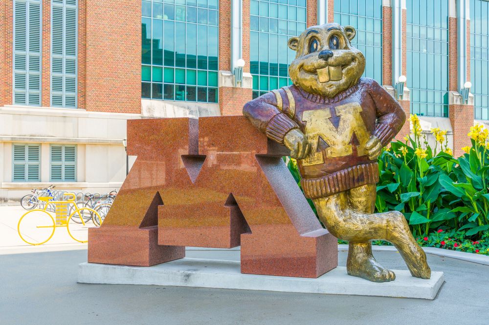 A statue of Goldy Gopher leaning against the UMN "M"